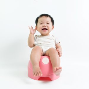Asian baby sitting on potty over white background